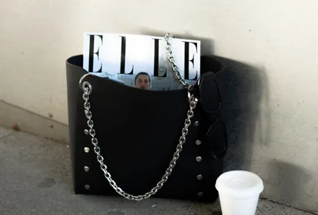 Bolso negro en el suelo con revista de elle