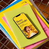 Un móvil que dice «Born to create» sobre una pila de cuadernos de colores